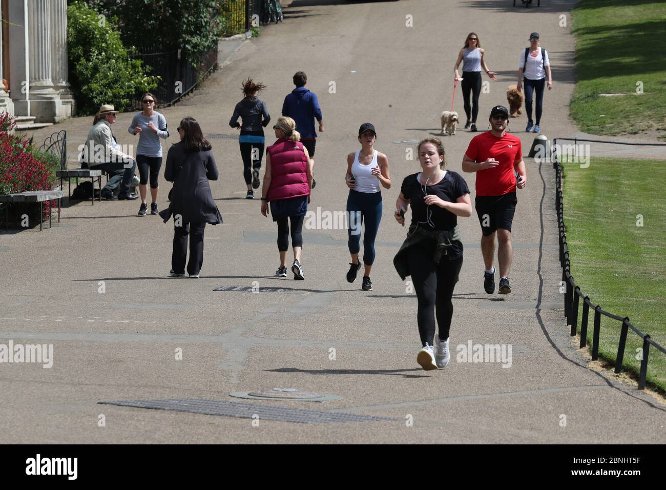 Joggers and walkers run on a footpath near the Italian Gardens in Hyde Park in London after the introduction of measures to bring the country out of lockdown. Stock Photo