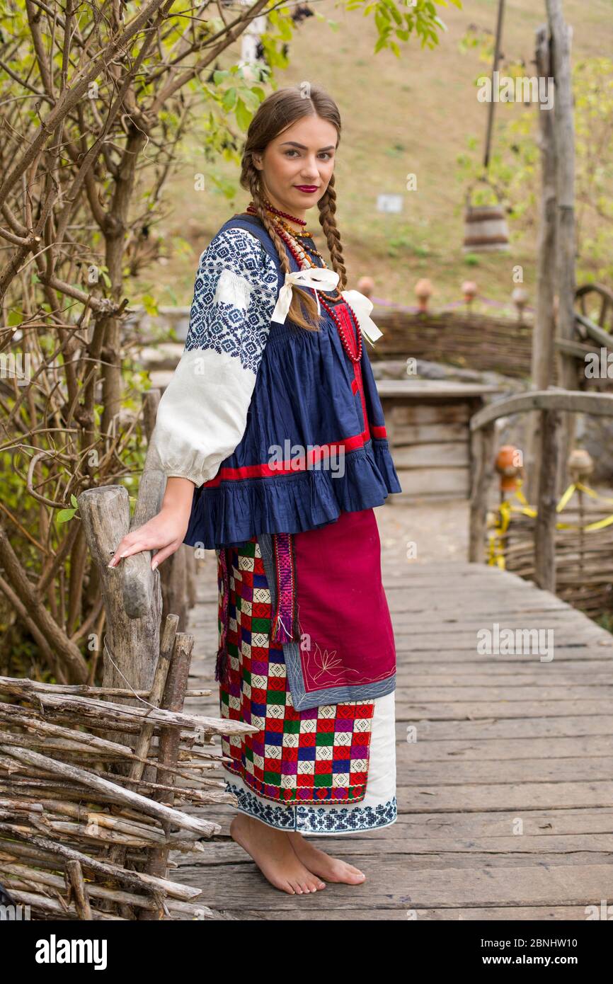 A girl in national dress is walking through an old bridge. Old clothes.  Retro staging of an ancient rite. Beautiful dress and skirt on a woman.  Beads Stock Photo - Alamy