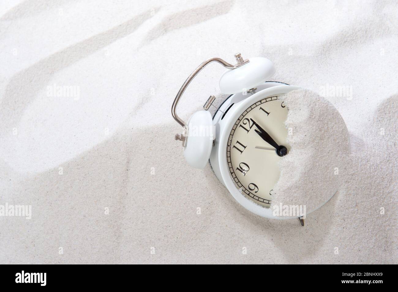Alarm clock in sand on beach. Vacation time concept Stock Photo