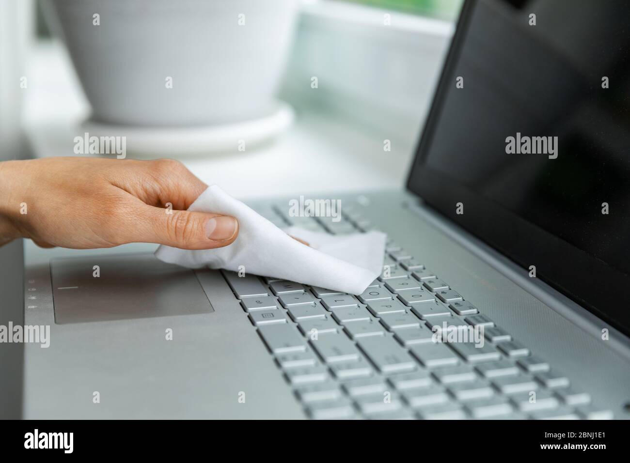 electronics disinfection and hygiene - hand cleaning laptop keyboard with antibacterial wet wipe Stock Photo