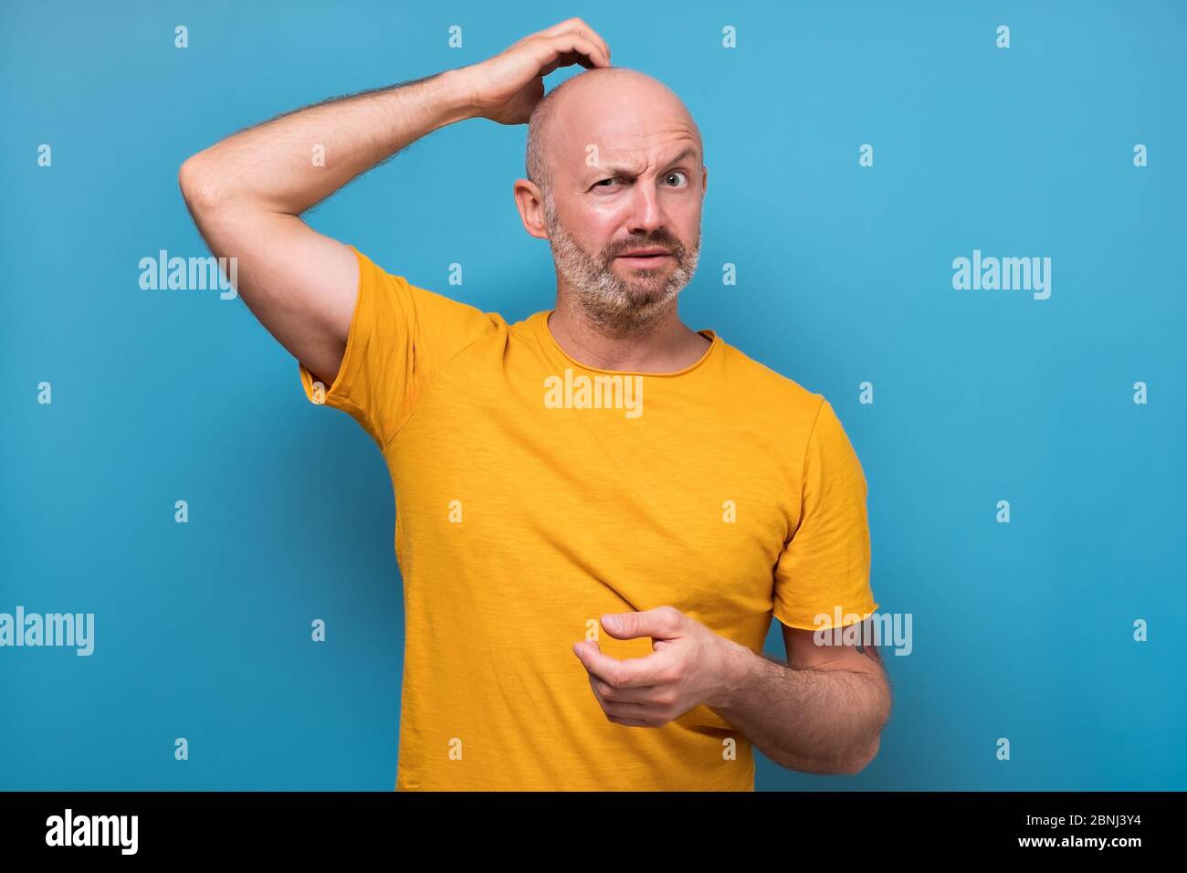 Mature man having doubts and with confuse face expression while scratching head Stock Photo