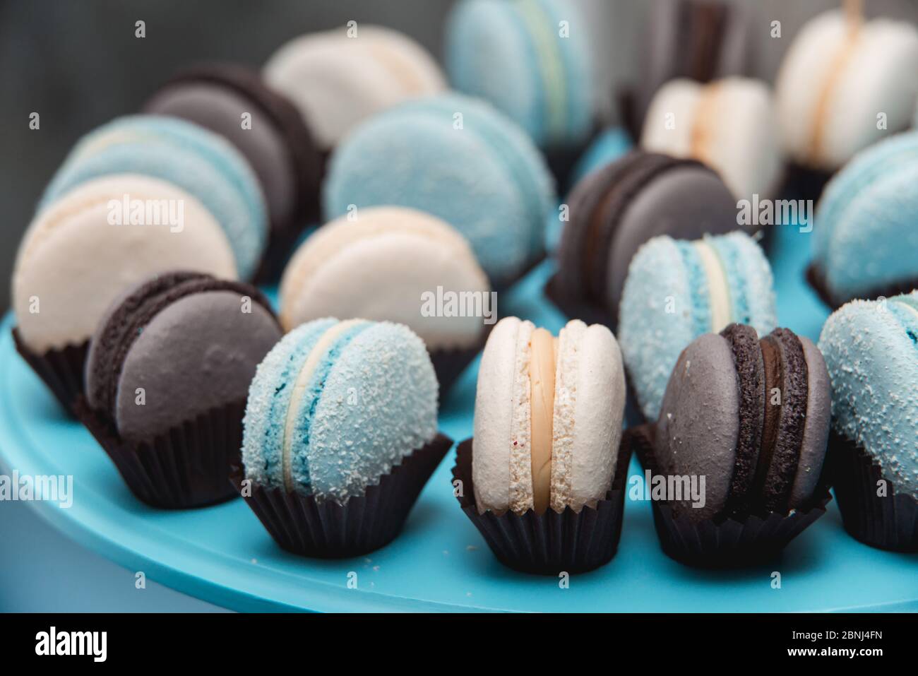 Light cream, blue and chocolate macaroons on blue stand. Food knolling concept Stock Photo