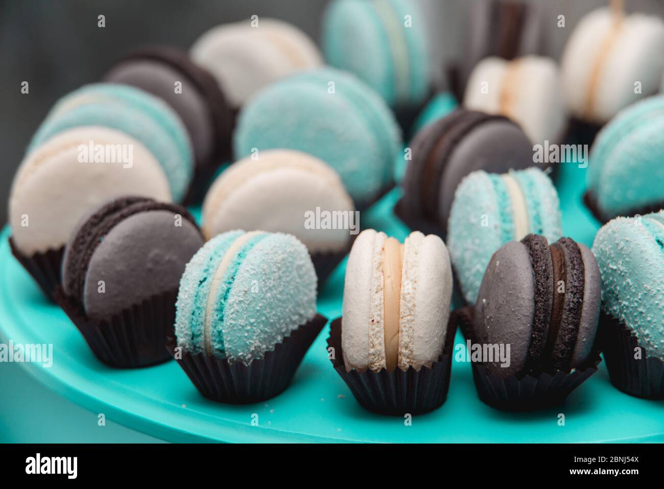 Light cream, tiffany blue and chocolate macaroons on tiffany blue stand. Food knolling concept Stock Photo