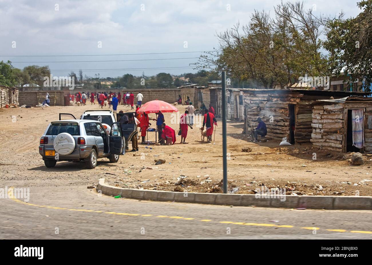 native village, small houses, people, two vehicles, wall, dirt street, lifestyle, Africa; Arusha; Tanzania Stock Photo