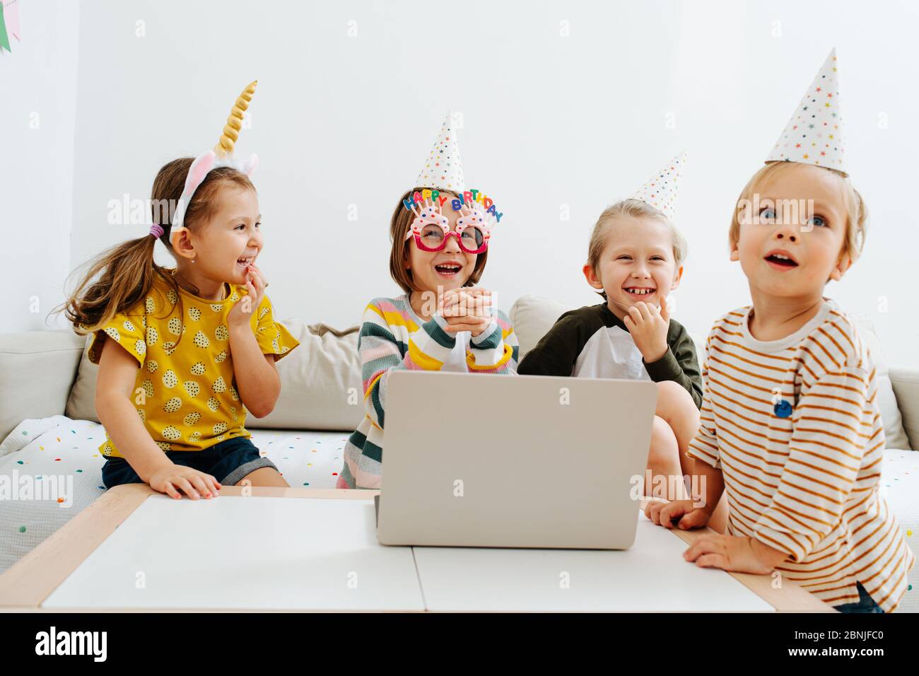 Four little kids having online birthday party on a quarantine at home Stock Photo