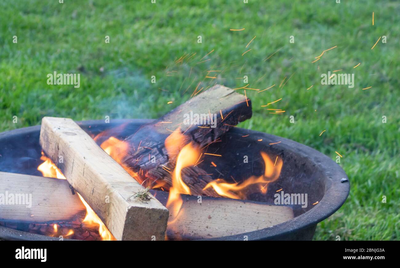 A crackling fire gently bursts with sparks from a modest firepit Stock Photo
