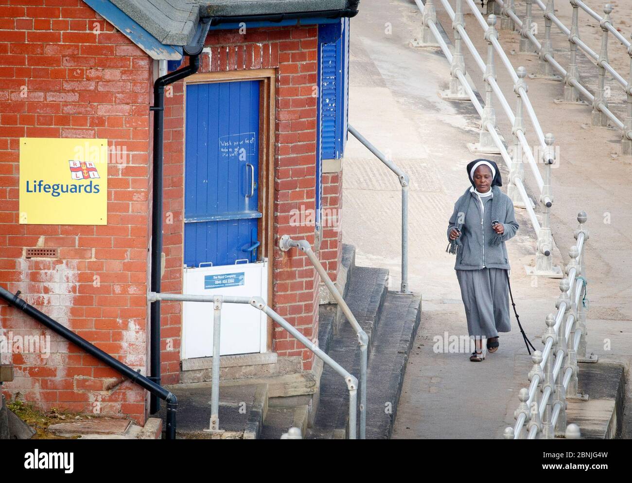 A woman walks along the sea front in Whitby, Yorkshire , after the introduction of measures to bring the country out of lockdown. Stock Photo