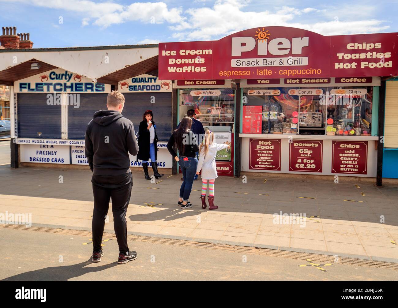 Poeple social distance as the queue at a kiosk near Scarborough beach in Yorkshire, after the introduction of measures to bring the country out of lockdown. Stock Photo