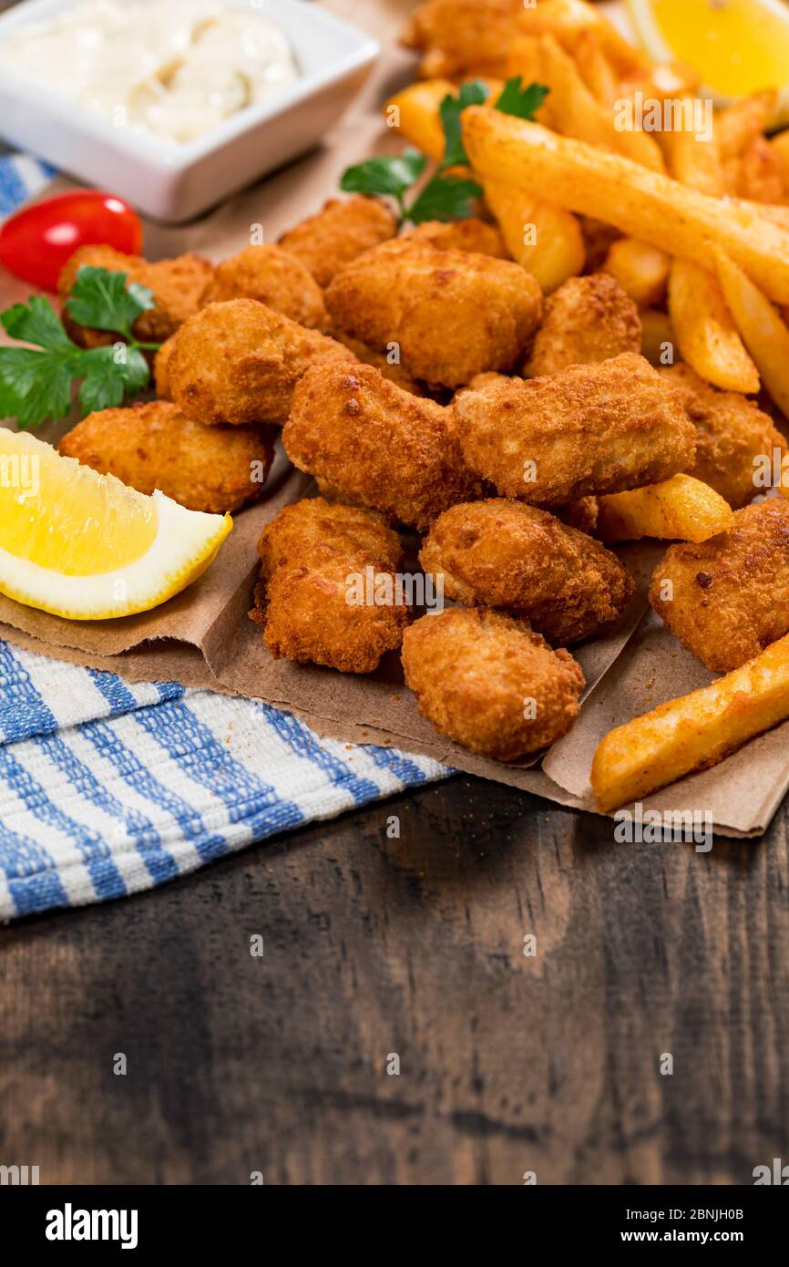 Crispy Fish Bites Snack Size. Deep Fried Pollock Fish Fingers with Tartar  Dipping Sauce on a Wooden Board Stock Photo - Alamy