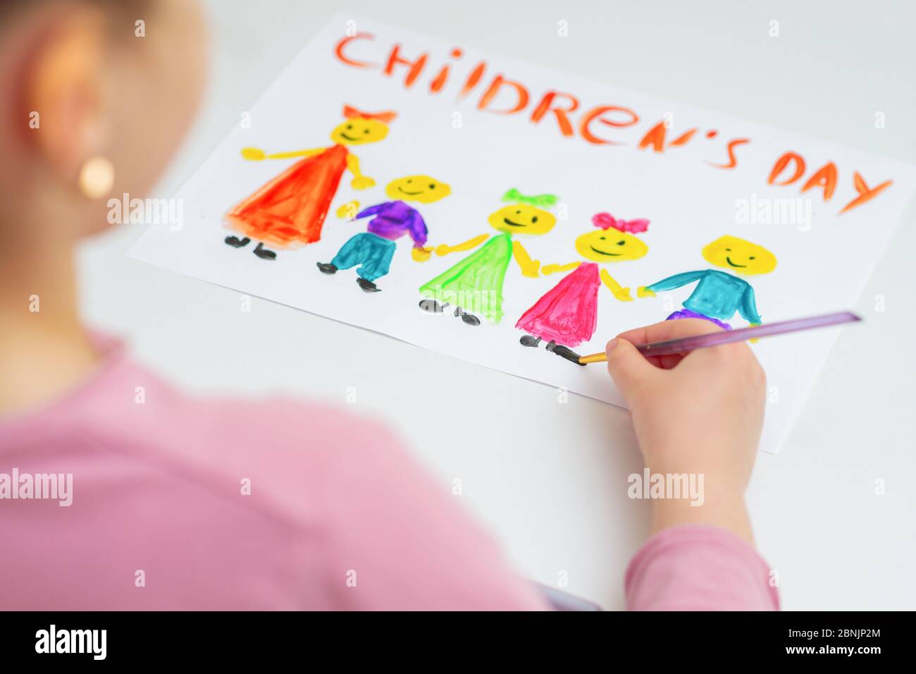 Girl is drawing the colorful children by watercolors with words Children's Day for the holiday Happy Children's Day. Stock Photo