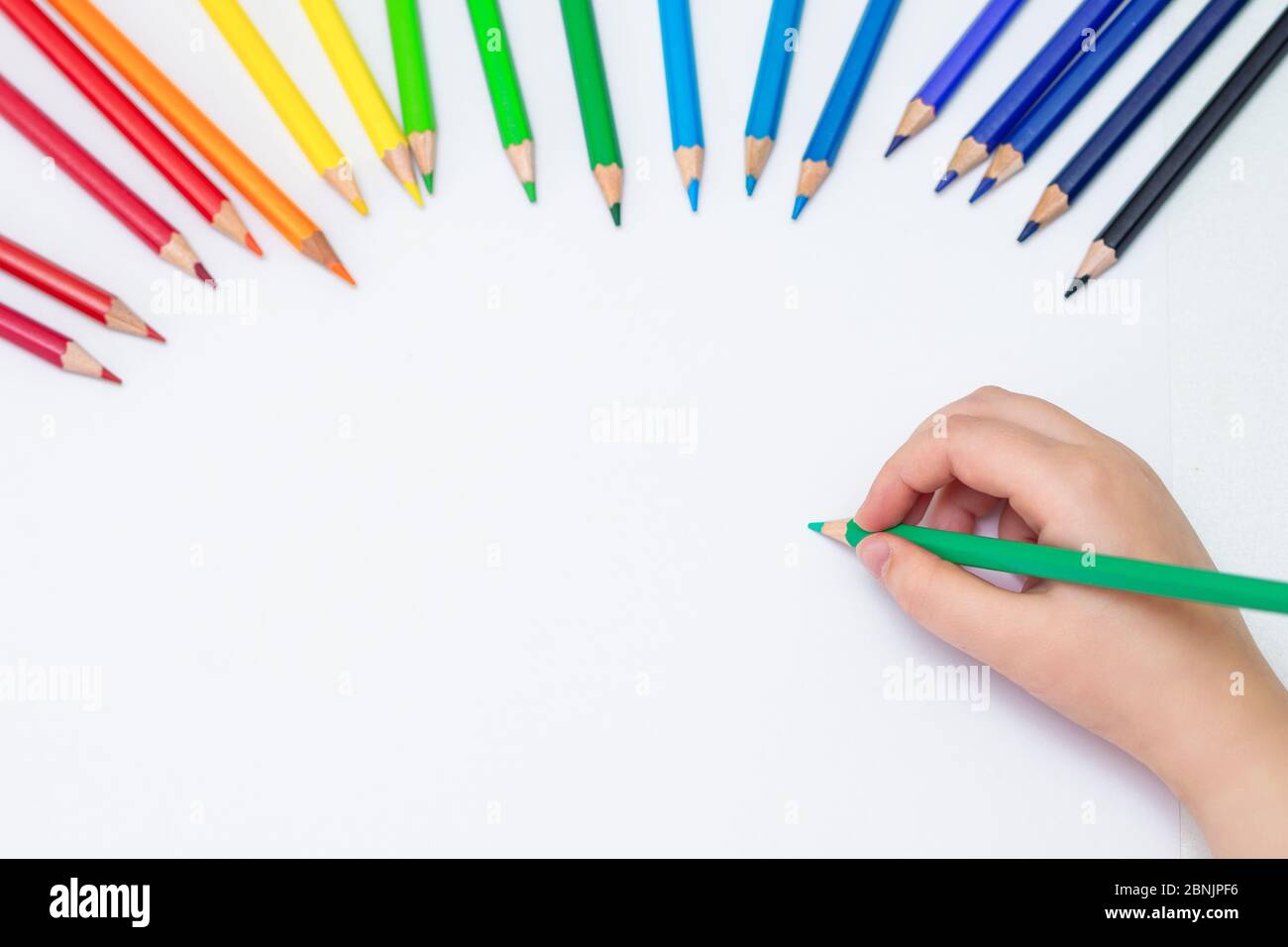 https://c8.alamy.com/comp/2BNJPF6/top-view-of-babys-hand-drawing-with-green-pencil-on-white-paper-with-the-set-of-colour-pencils-kids-painting-concept-copy-space-for-text-mockup-2BNJPF6.jpg