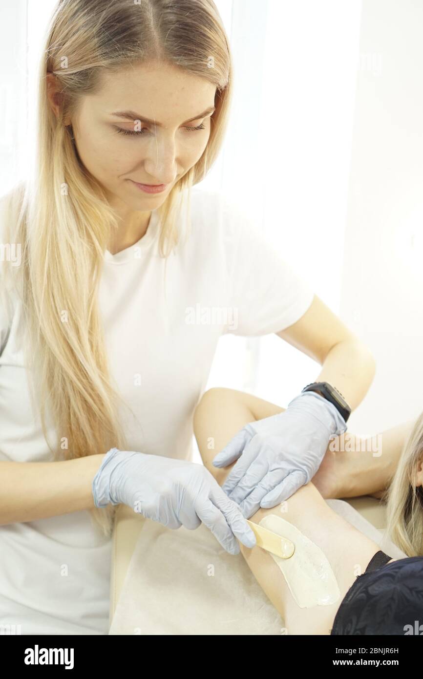 Waxing woman armpit with spatula. Salon wax beautician epilation
