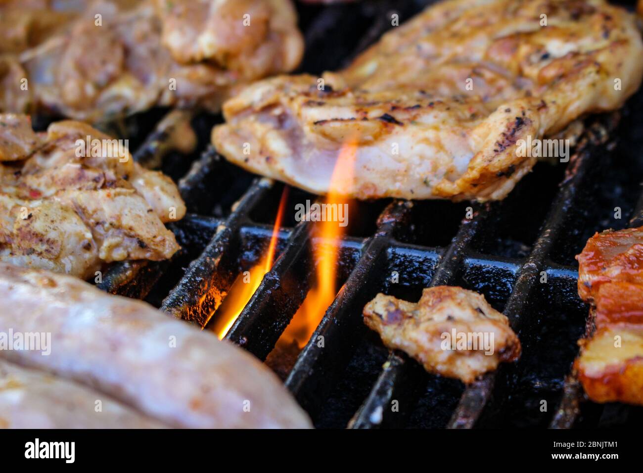 Meat being flame grilled on a barbecue, BBQ flame grill Stock Photo - Alamy
