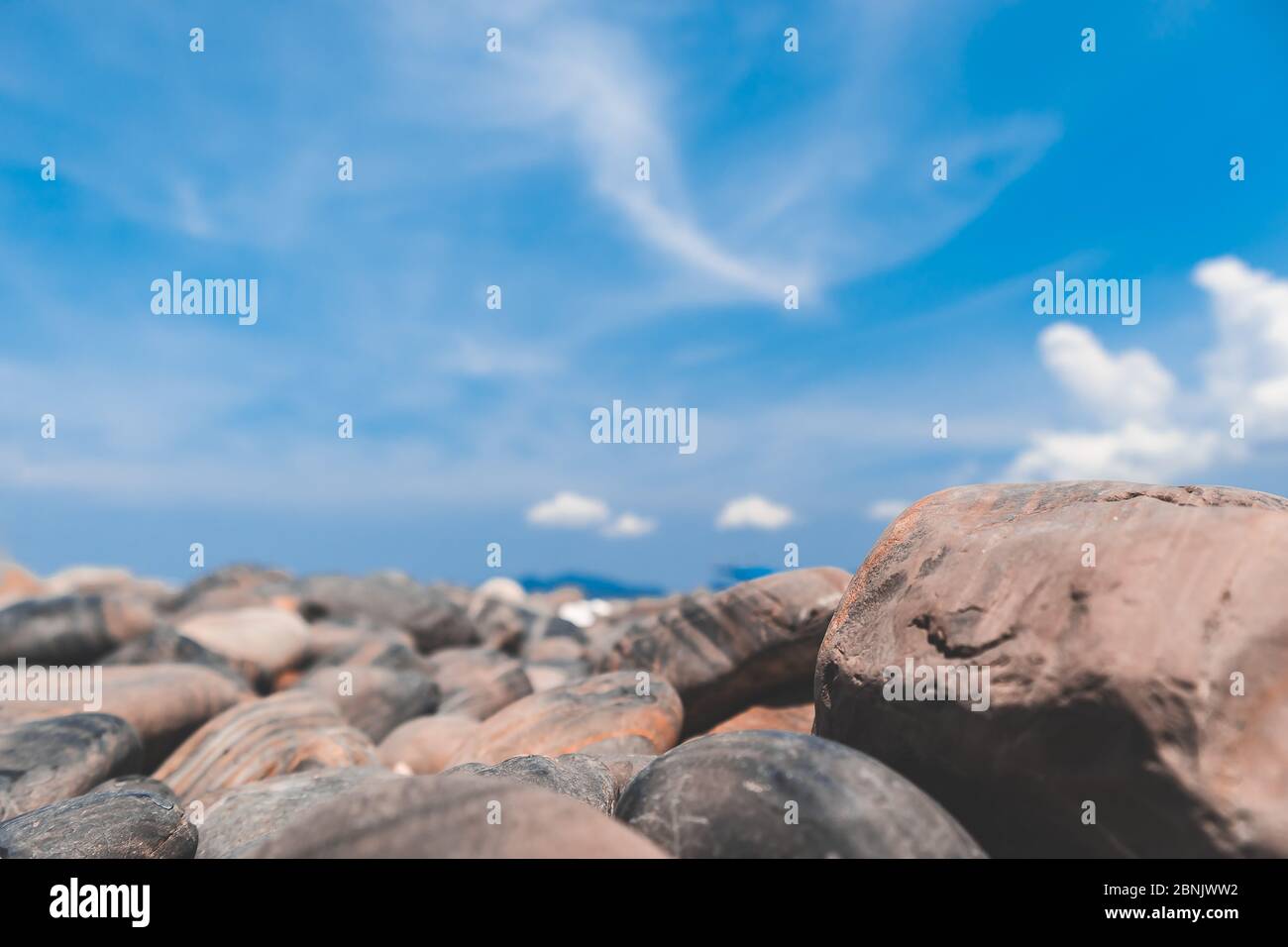 Pebble stone beach on blue sky background with shallow depth of field Stock Photo