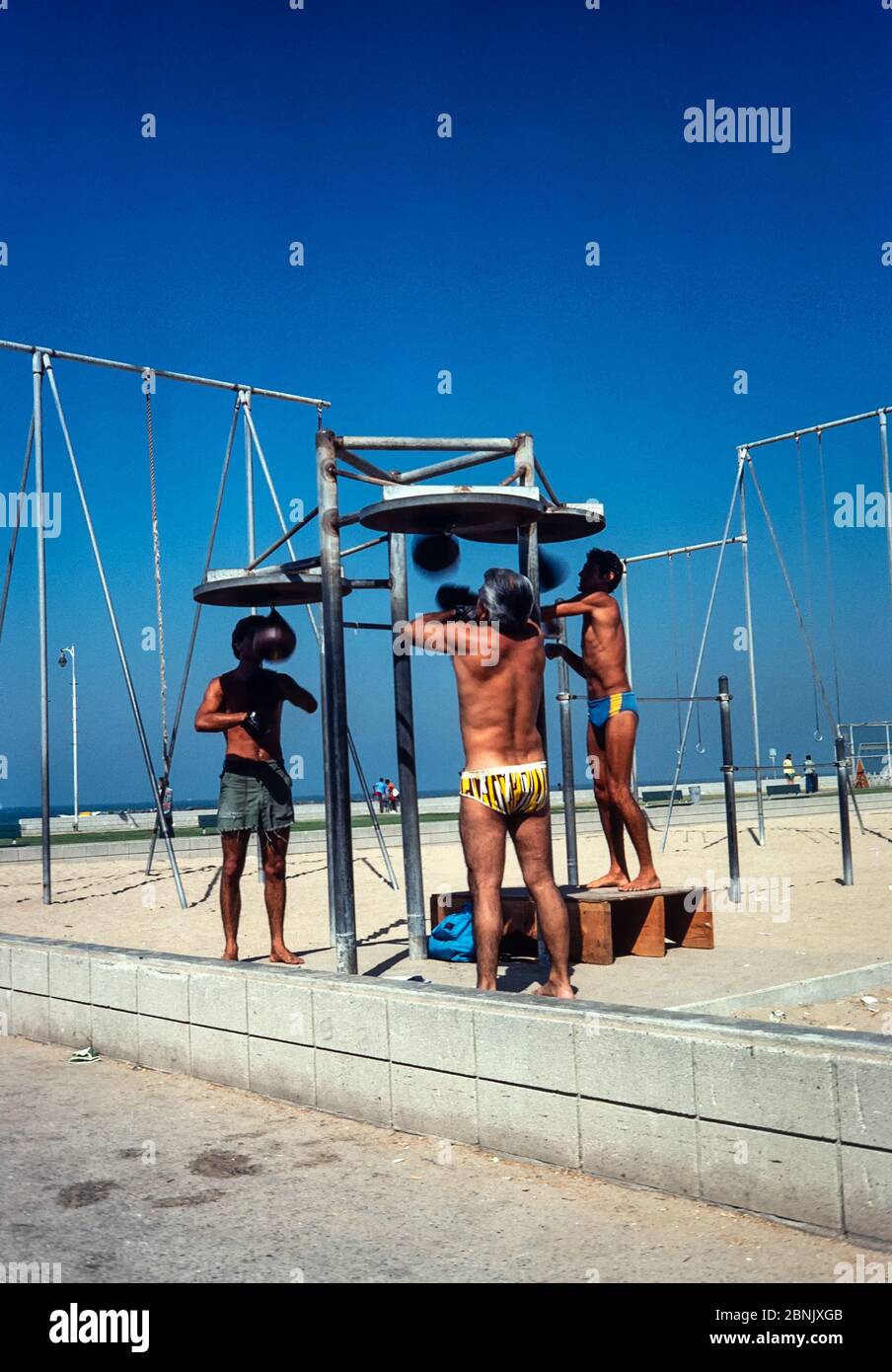 Venice, California, USA - Aug 1980: People exercising using outdoor gym  equipment on the beach at Venice, Los Angeles, California.  Scanned 35mm film. Stock Photo