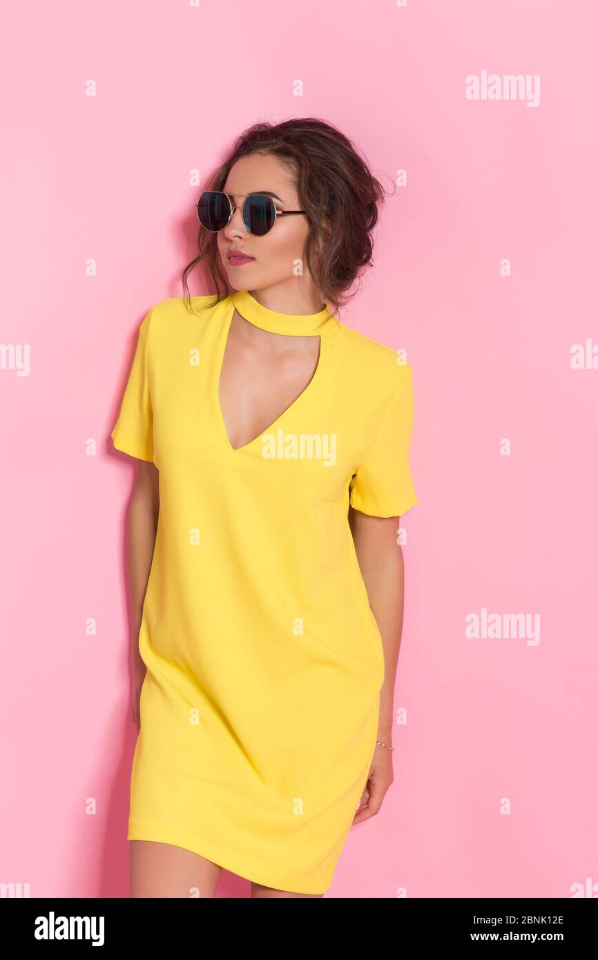 Beautiful girl wearing yellow dress and sunglasses posing on pink ...