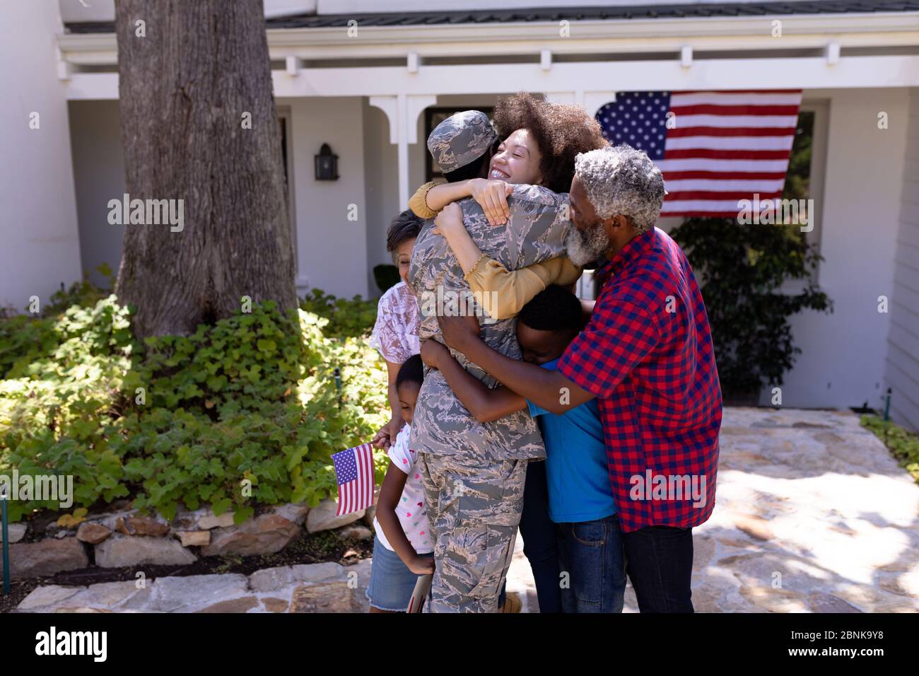 Multi-generation mixed race family welcoming an African American man wearing military uniform Stock Photo