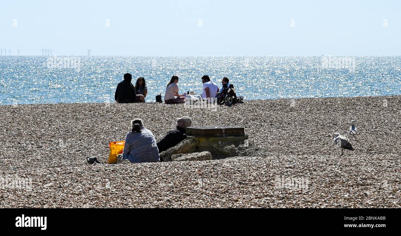 Brighton UK 15th May 2020 - People gather on Brighton beach and seafront during a sunny day on the South Coast . However Brighton's MPs are hoping crowds don't descend on the seafront this weekend the first after the governments slight easing of lockdown restrictions in England during the coronavirus COVID-19 pandemic . Credit: Simon Dack / Alamy Live News Stock Photo