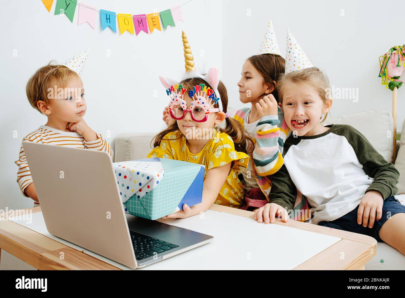 Little girl showing birthday present on a webcam, surrounded by friends Stock Photo