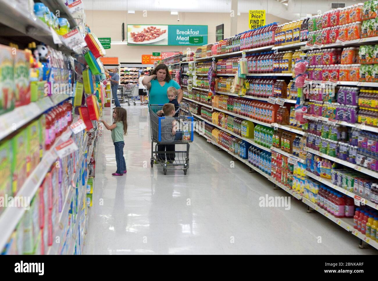 White female mom with her children pushes shopping cart along aisle of a San Marcos, Texas Wal