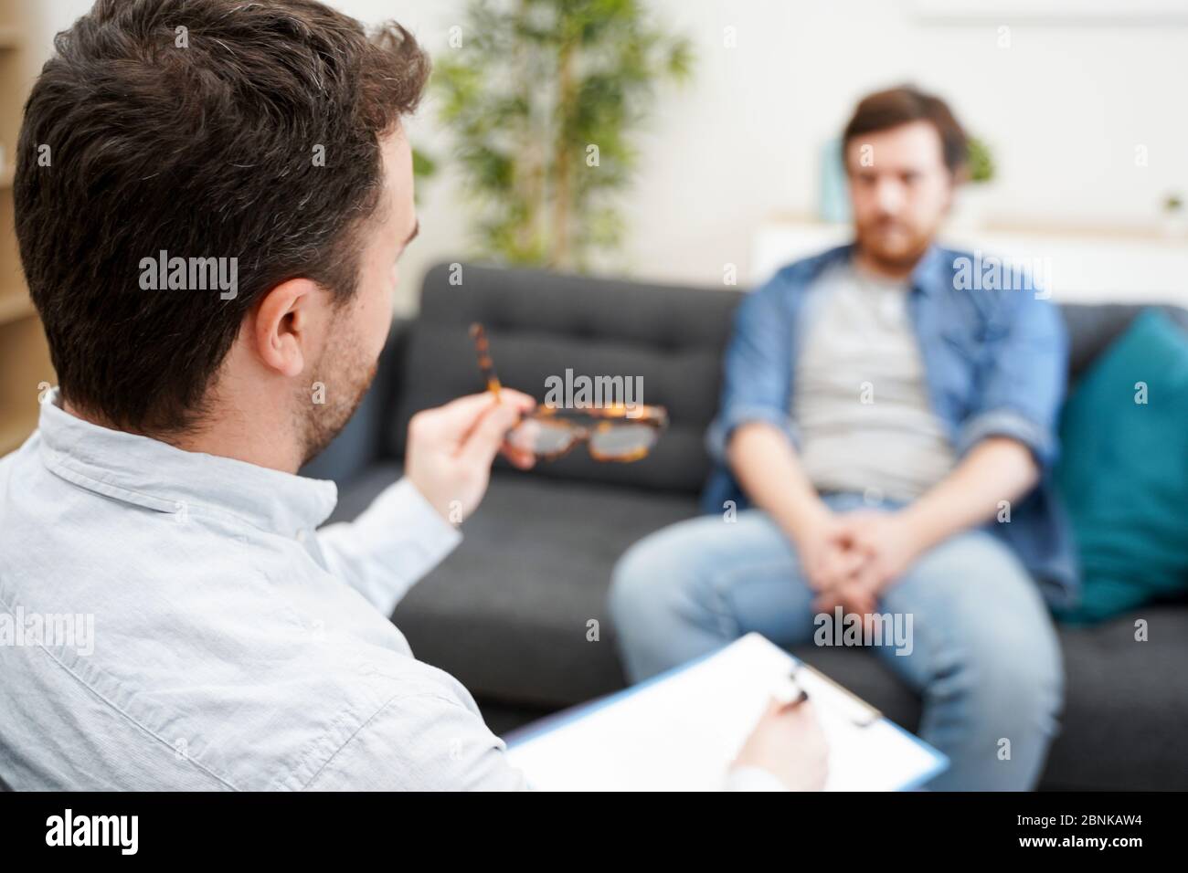 Psychologist doctor taking notes during psychotherapy session Stock