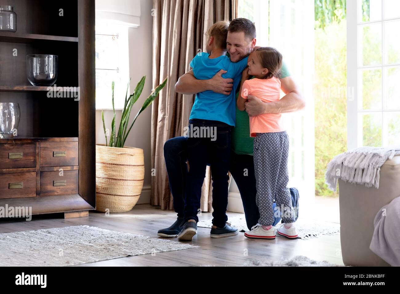 Caucasian girl and boy welcoming their father in their house Stock ...