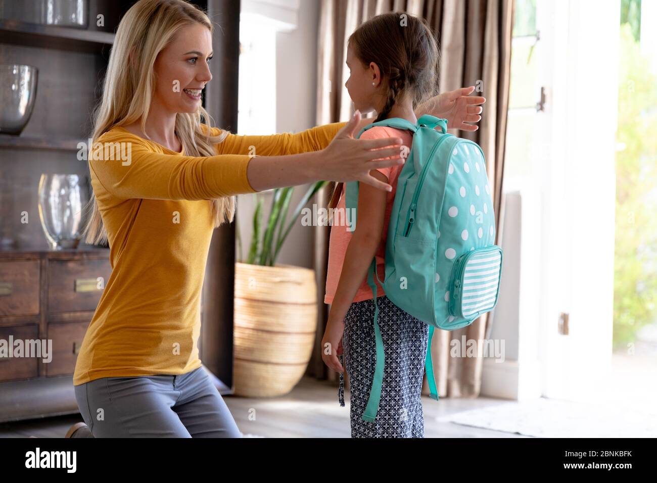 Caucasian woman helping her daughter preparing for leaving to school. Stock Photo