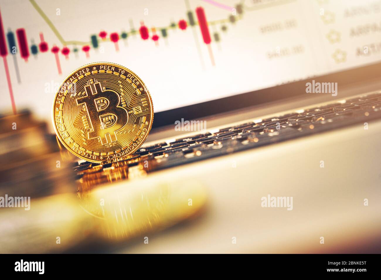 Golden Bitcoin Leaning On Laptop Keyboard With Performance Graphs On Computer Screen. Stock Photo