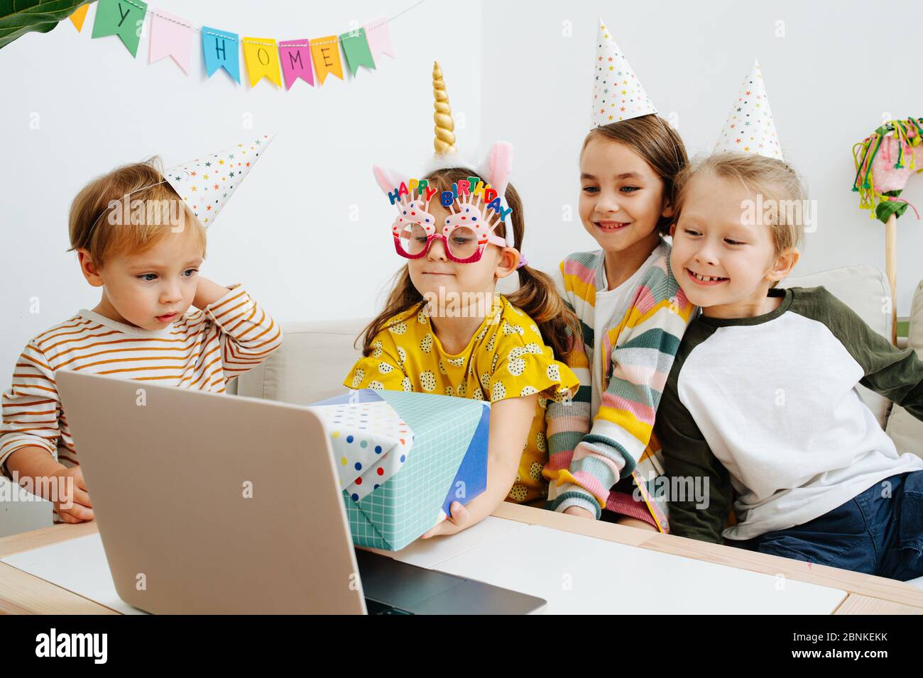 Little girl showing birthday present on a webcam, surrounded by siblings Stock Photo