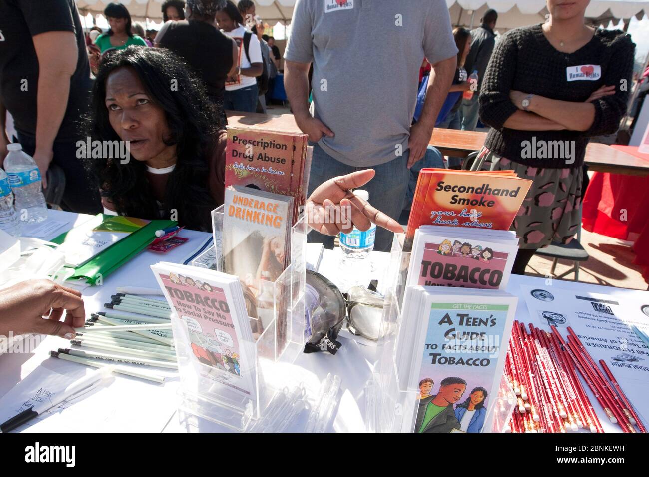 Austin Texas USA, January 21, 2013: Woman talks to passer-by about health-related brochures covering facts for teens about tobacco use, prescription drug abuse, and alcohol use during outdoor festival at small college campus. Stock Photo