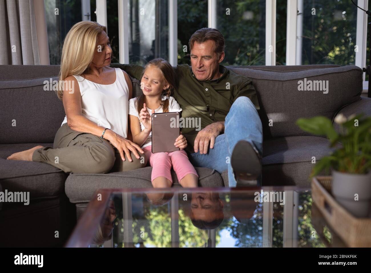 Portrait of a Caucasian girl and her grandparent using a digital tablet on a couch Stock Photo