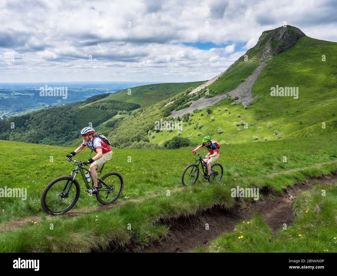 Single trail with mountain bikers on the descent from the mountain 'La banne d'ordanche', a volcanic peak (1 512 m) in the Monts Dore in the French 'Département de Puy-de-Dôme'. Stock Photo
