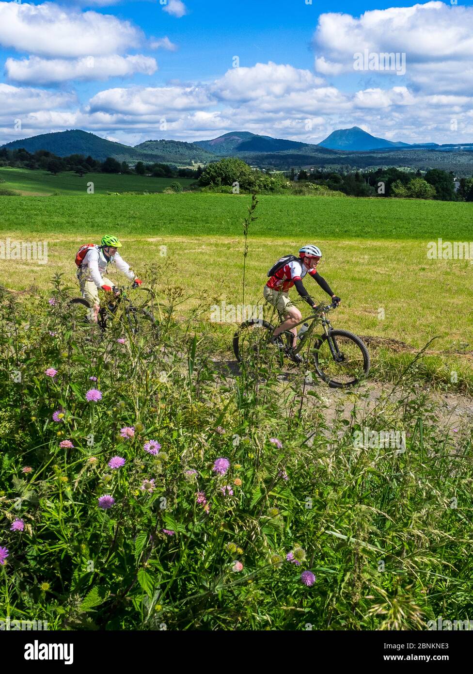 Biking on track near the french village Phialeix. In the background: the 'Puy de Dôme' (1465m), a volcanic summit in the Massif Central. It belongs to the 'Chaîne des Puys', the mountain chain of 'the puys', with 80 volcanoes Stock Photo