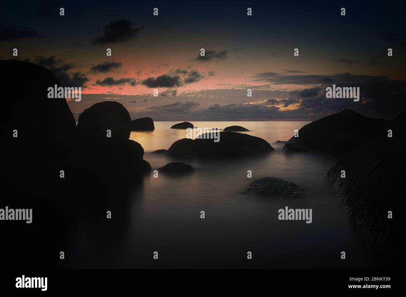 A long exposure during dusk at Sai Nuan beach on the west coast of Koh Tao, Thailand. The image shows granite formations Stock Photo