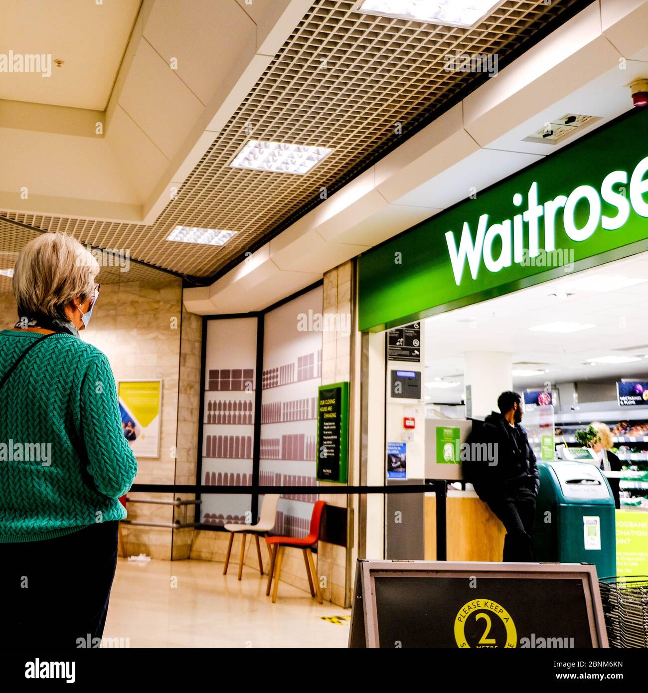 Woman Standing In Line To Enter Waitrose Supermarket Observing Social Distancing During The Coronavirus Outbreak Stock Photo