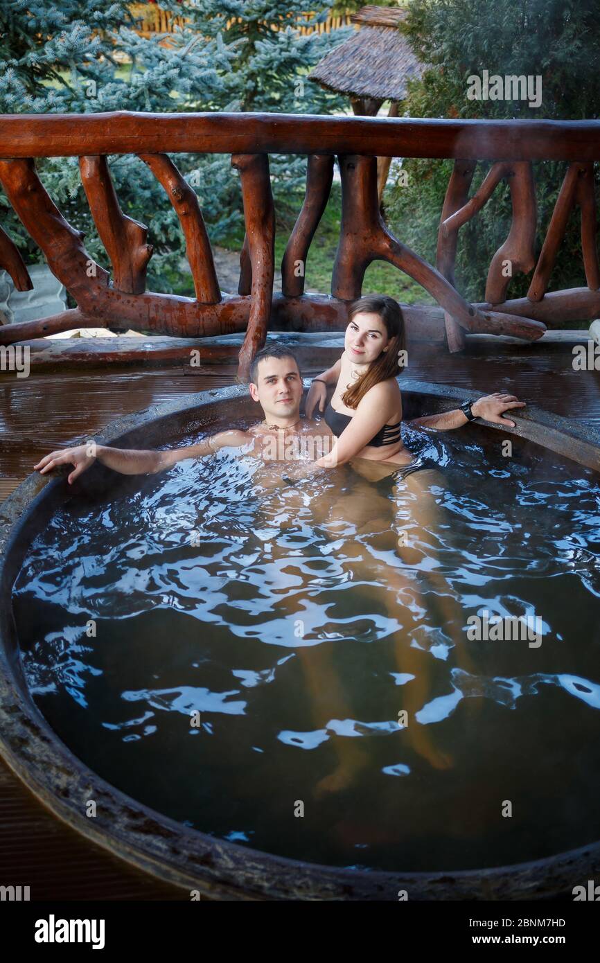 Happy romantic couple taking a bath in a jacuzzi, outdoors on a