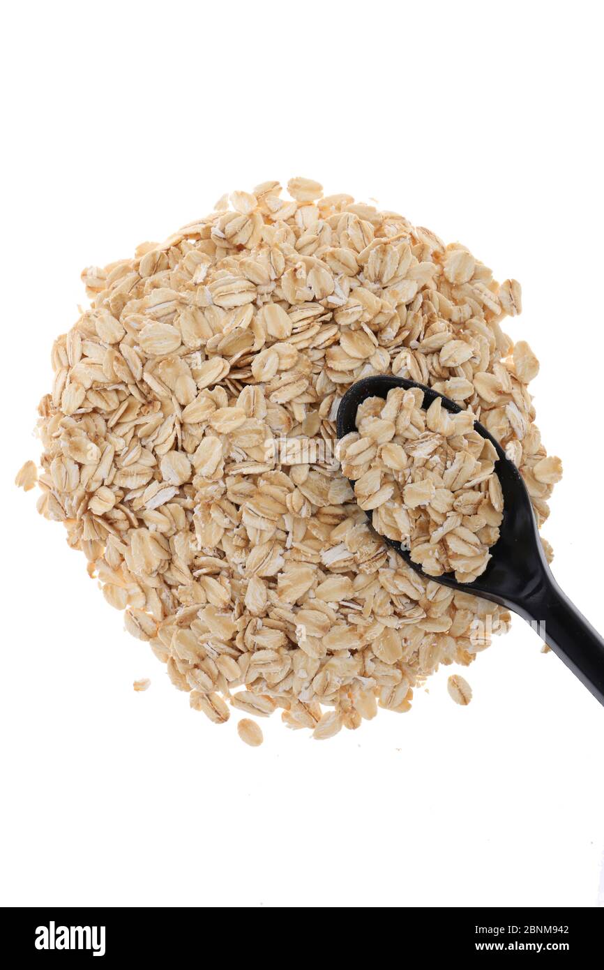Oat flakes, uncooked oats in bowl with poon and wheat ears on white