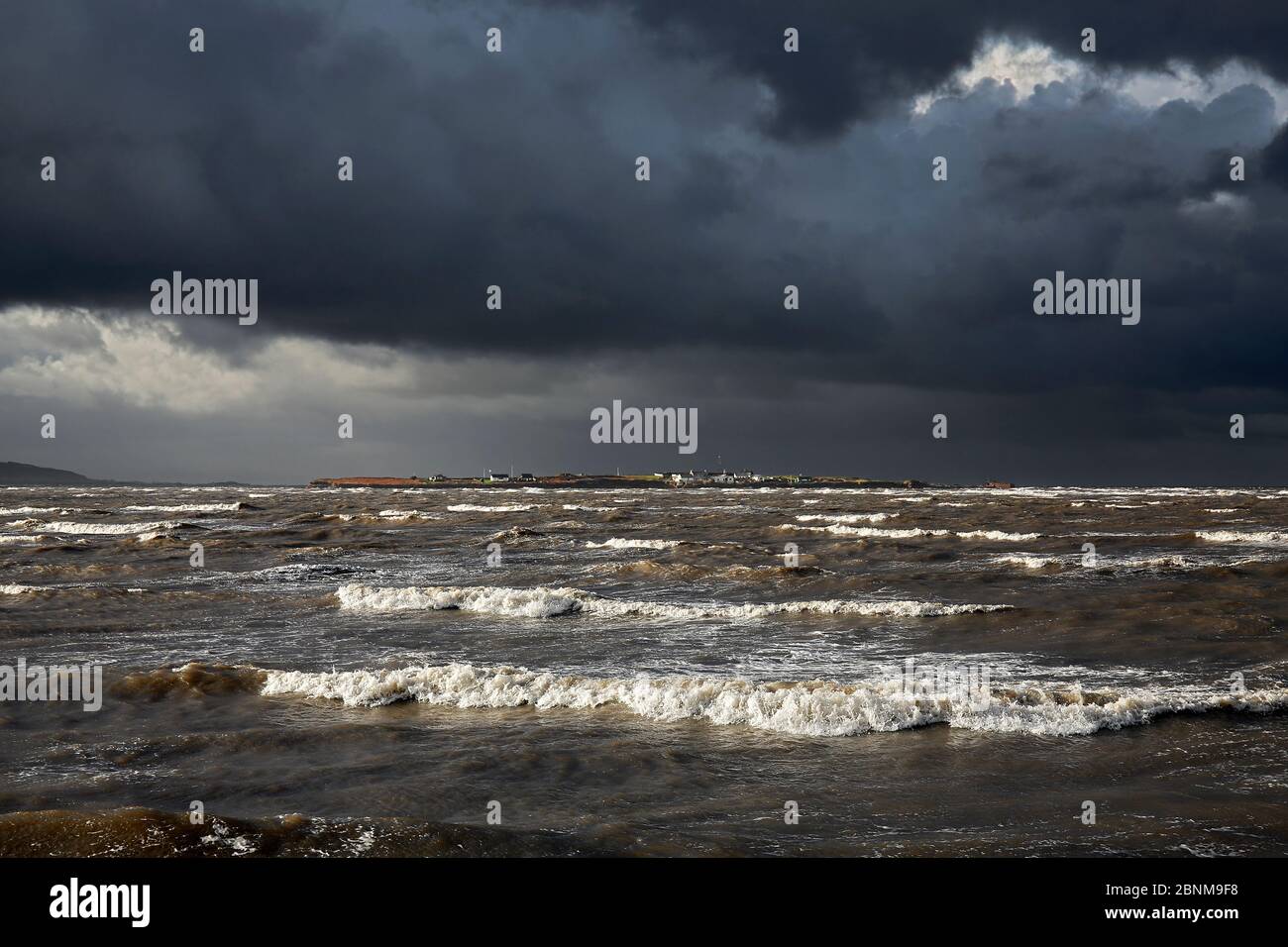 Hilbre Island viewed at high tide with gathering storm clouds from