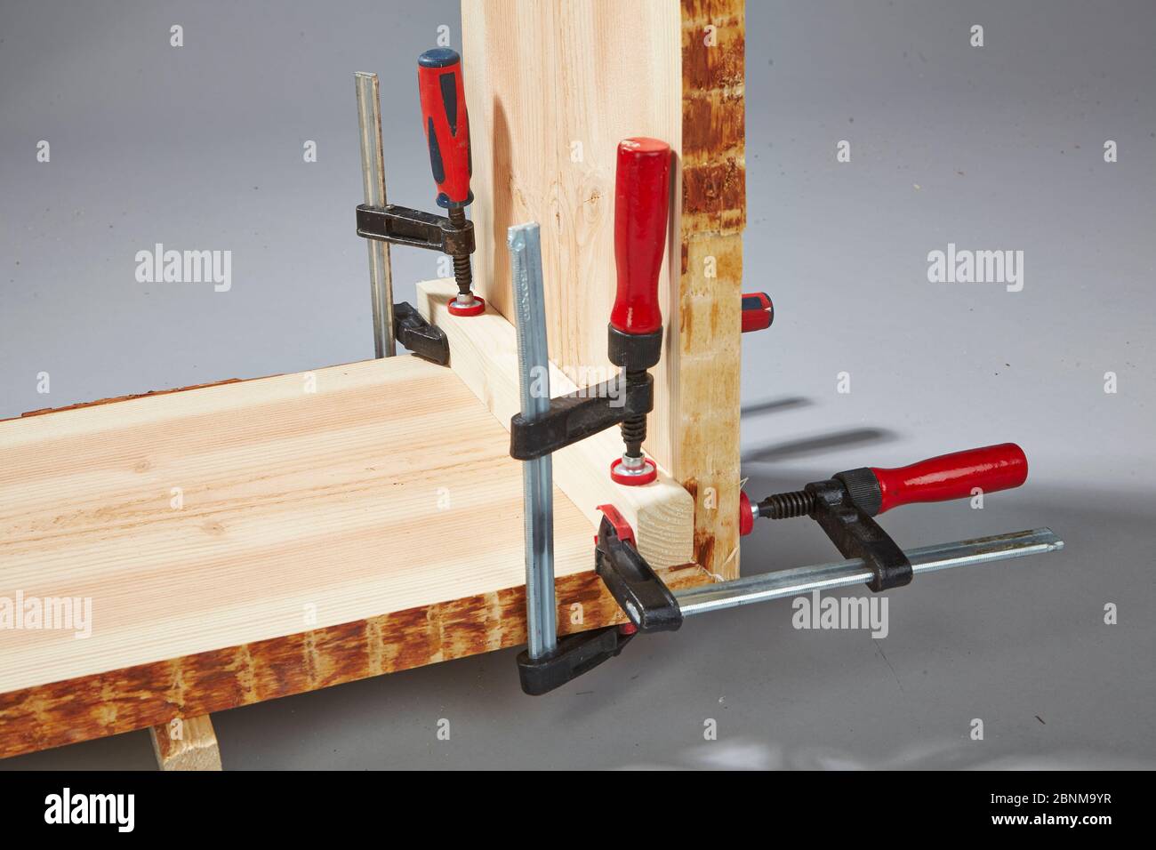 Construction of a shelf made of wood, do-it-yourself production, step-by-step, step 8 Stabilization of the fresh gluing with the help of screw clamps and an auxiliary bar that is removed after curing. Stock Photo