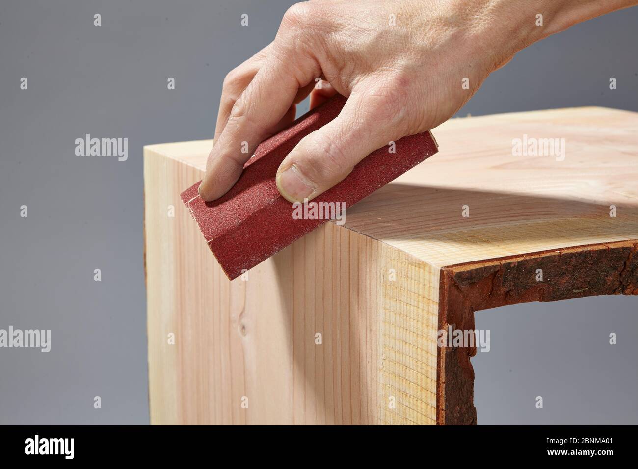 Building a wooden shelf, do-it-yourself production, step-by-step, step 9 Sanding the outer edge after the glue has hardened with the help of a sanding block Stock Photo