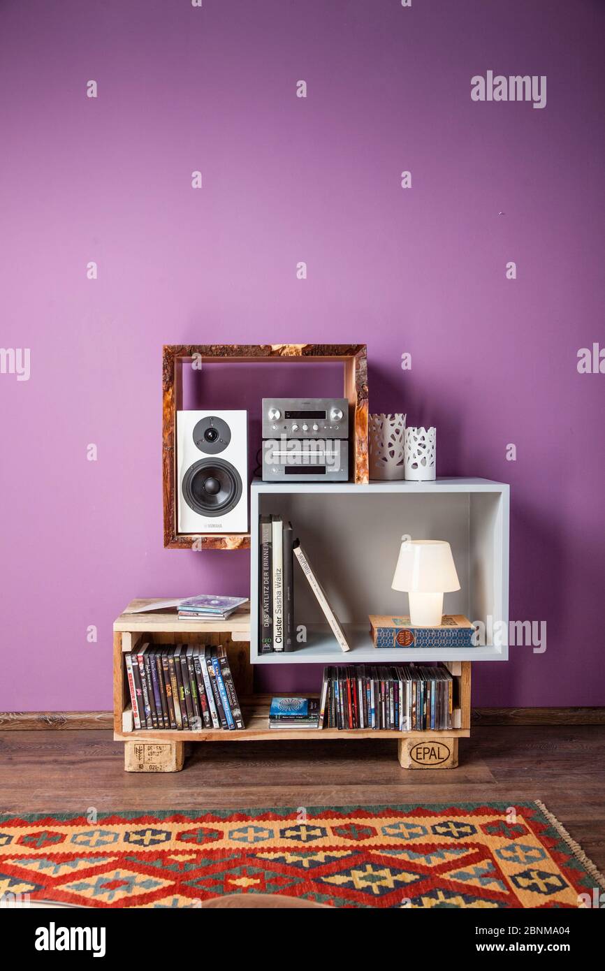 Construction of a shelf made of wood, Euro pallet, solid wood, MDF board; Do-it-yourself production step-by-step, final photo 01 in the living room in front of a purple wall on a wooden floor Stock Photo