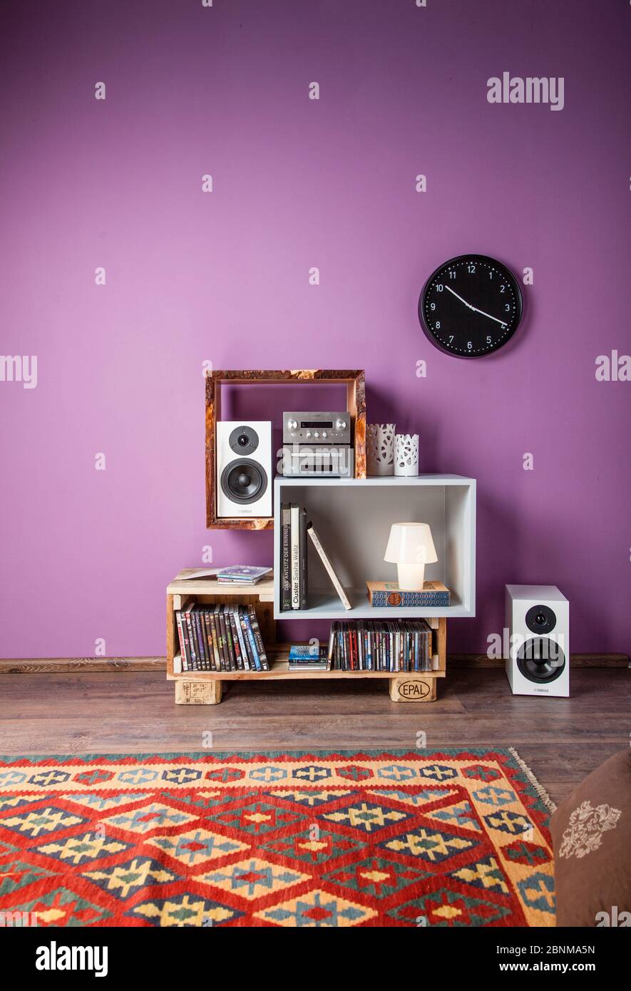 Construction of a shelf made of wood, Euro pallet, solid wood, MDF board; Do-it-yourself production step-by-step, final photo 02 in the living room in front of a purple wall on a wooden floor Stock Photo