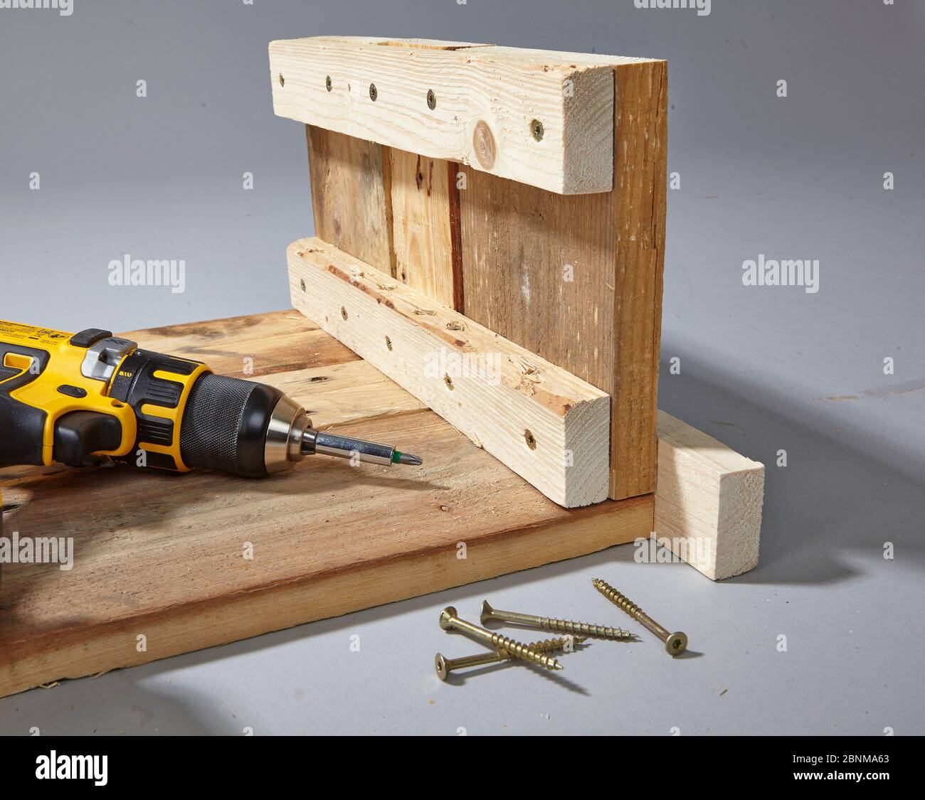 Construction of a shelf made of wood, Euro pallet, solid wood, MDF board; Do-it-yourself production, step-by-step, step 5 connecting the elements with screws, cordless screwdriver Stock Photo