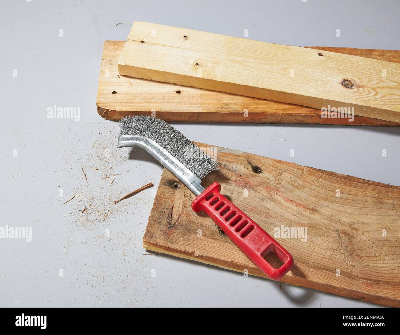 Construction of a shelf made of wood, Euro pallet, solid wood, MDF board; Do-it-yourself production, step-by-step, step 2b removal of coarse dirt and wood chips with a wire brush Stock Photo