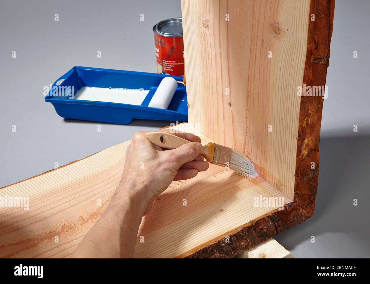 Construction of a shelf made of wood, do-it-yourself production, step-by-step, step 17a painting the finished glued furniture with water-soluble acrylic paint, first painting the corners with a brush, then painting the surfaces with a foam roller Stock Photo