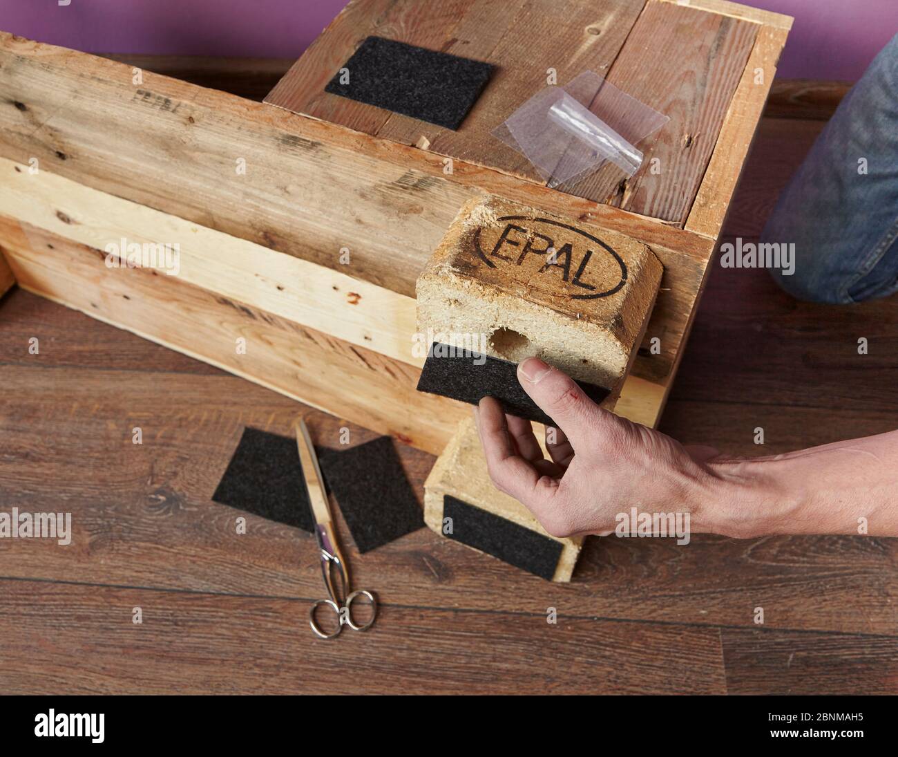 Construction of a shelf made of wood, Euro pallet, solid wood, MDF board; Do-it-yourself production, step-by-step, step 18, attaching self-adhesive felt panels under the furniture feet Stock Photo