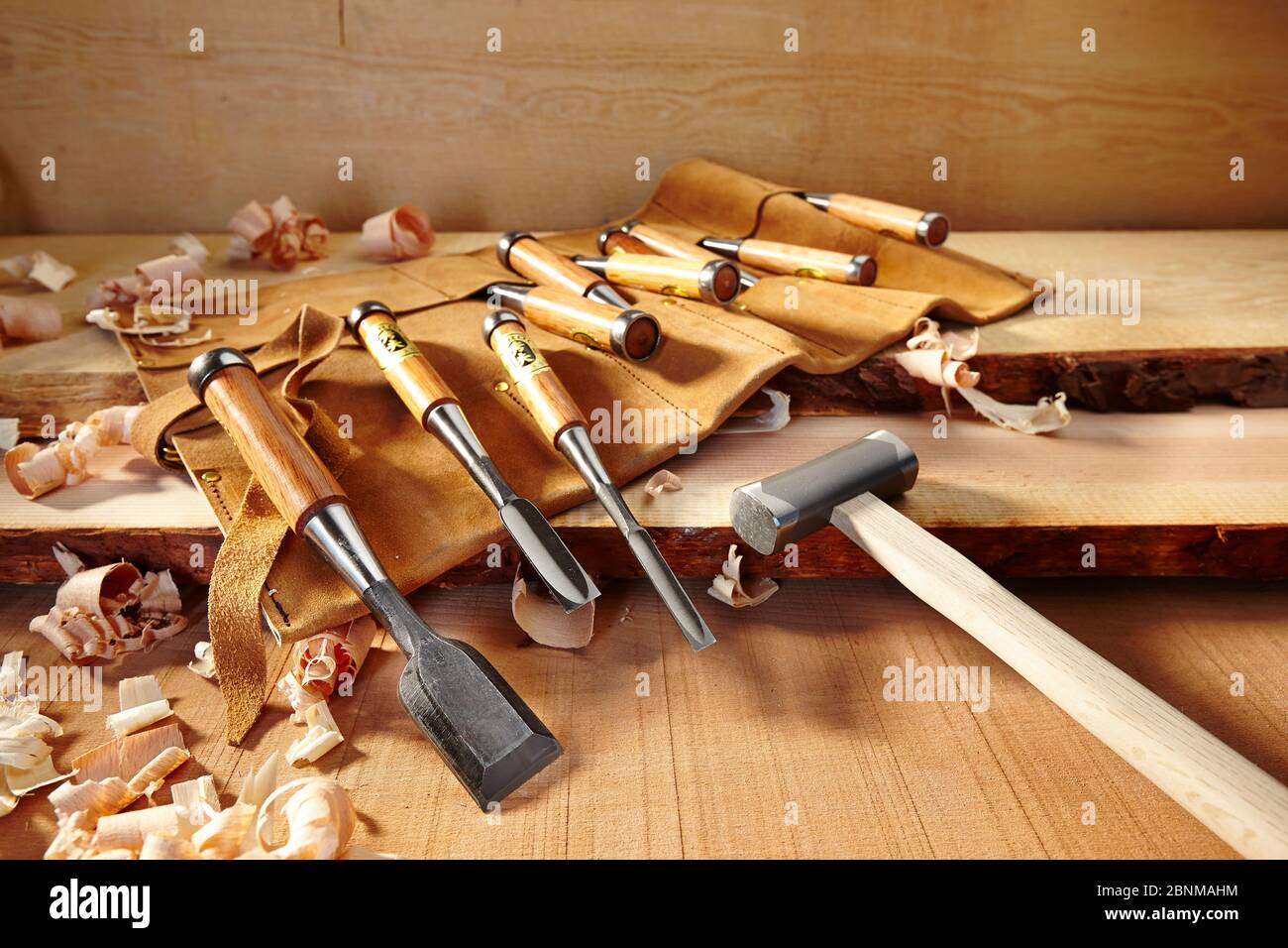 Woodworking tools from Japan, series, Japanese woodworking tools, overview of various wood chisels and hammer, partly in a leather roll case, arranged on wood with wood shavings Stock Photo