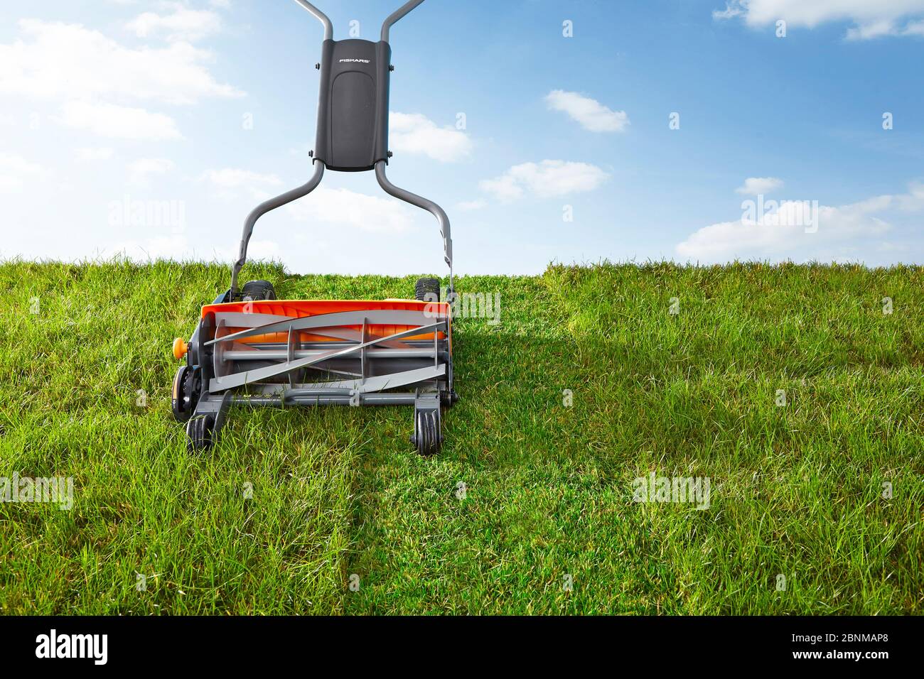 Spindle mower on lawn against light blue hires stock photography and