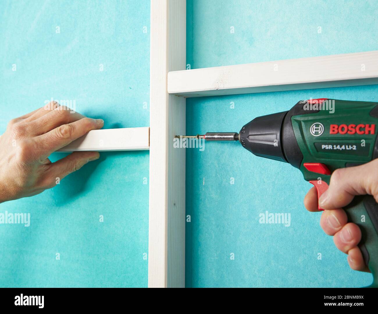 DIY wall design 02, step-by-step do-it-yourself production, various turquoise colored areas separated by white wooden strips, step 12: connecting the vertical and horizontal wooden strips with screws Stock Photo
