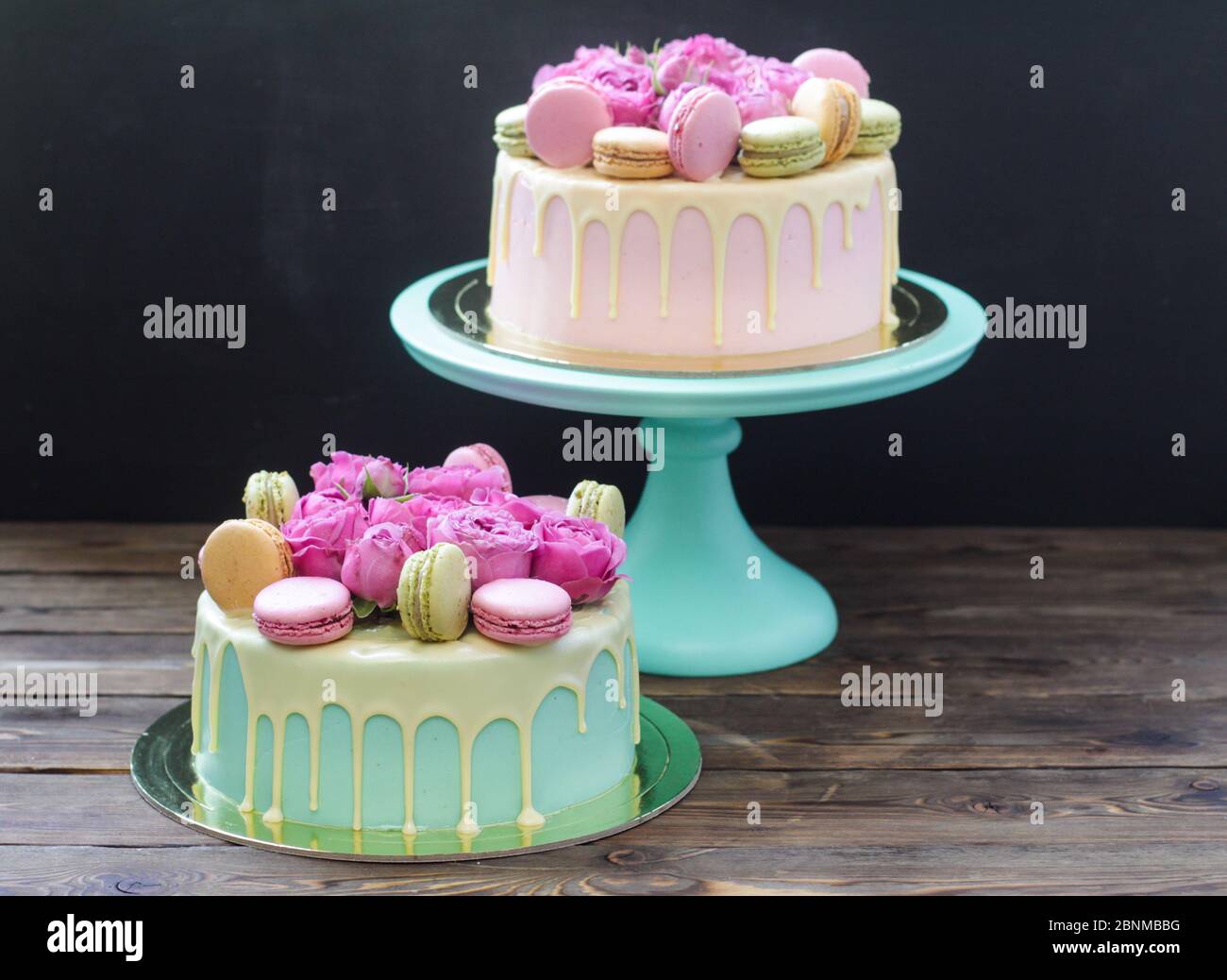 Modern pink cake with melted chocolate, fresh roses and macaroons ...